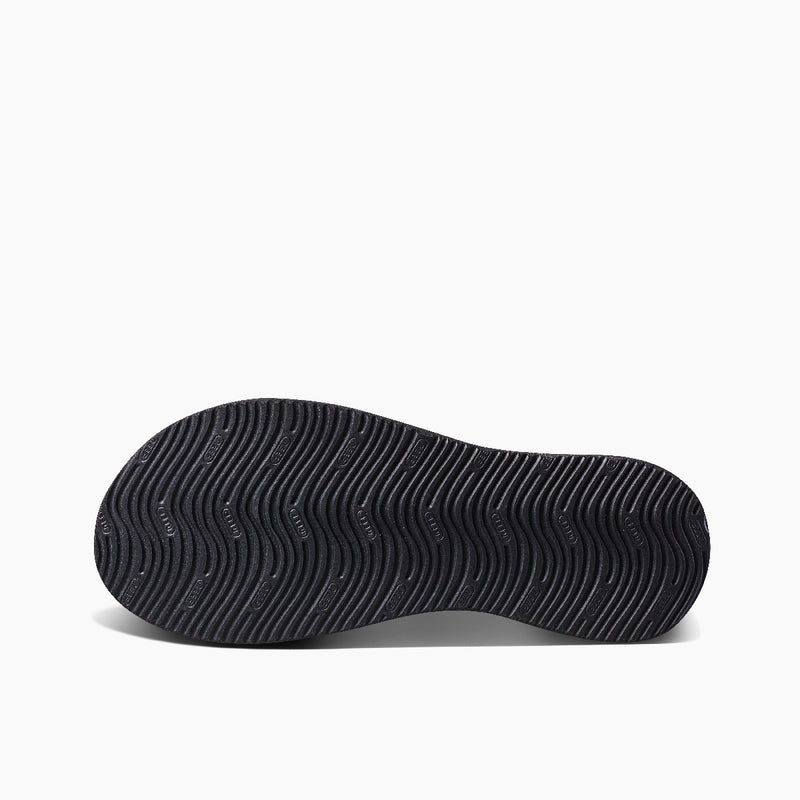 Reef Cushion Phantom 2.0 sandal outsole in black showing wave-like tread pattern for enhanced grip, bottom view.