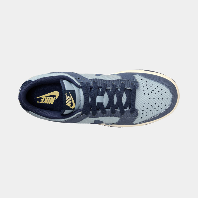 Nike Dunk Low Retro SE sneakers top view featuring a blue and pale blue canvas upper, perforated toe box, blue laces, and Nike branding.