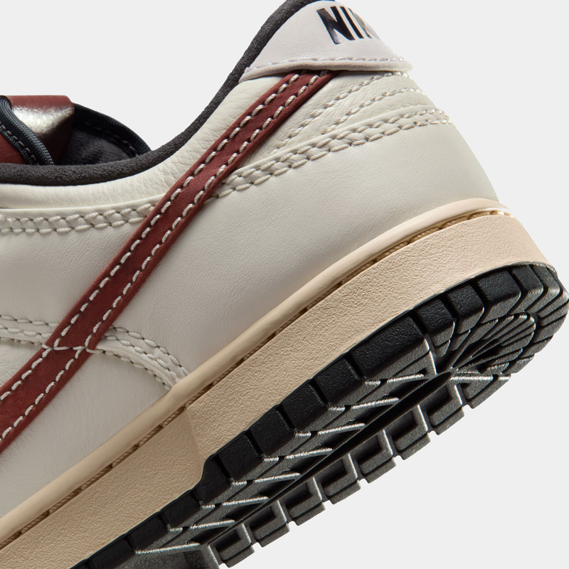 Nike Dunk Low sneakers in cream with burgundy accents, detailed stitching, and black outsole, back and sole close-up view.