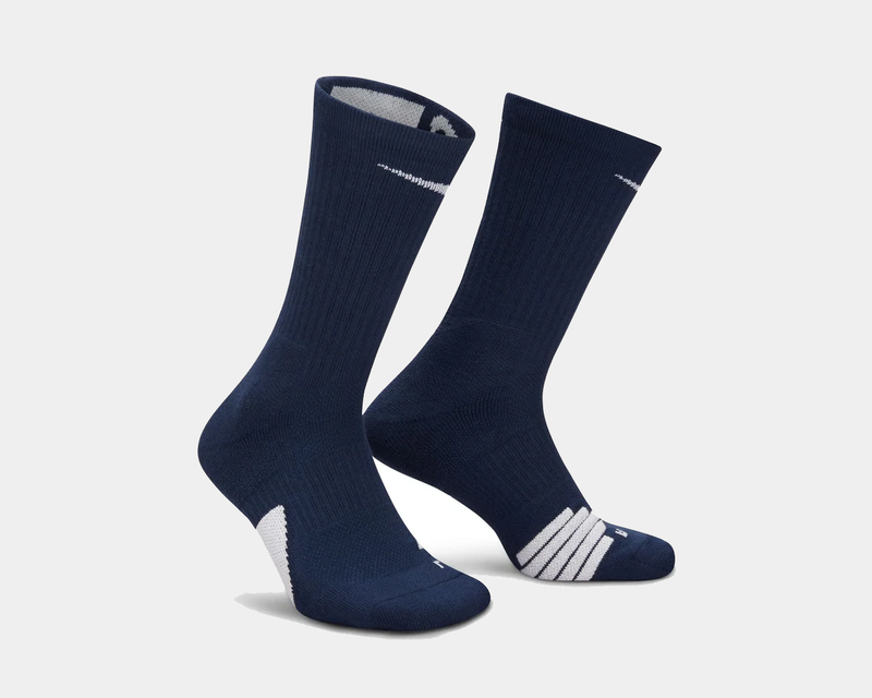 Nike Elite Crew socks in navy blue with white accent details and ribbed texture, angled side view showing arch support and reinforced toe.