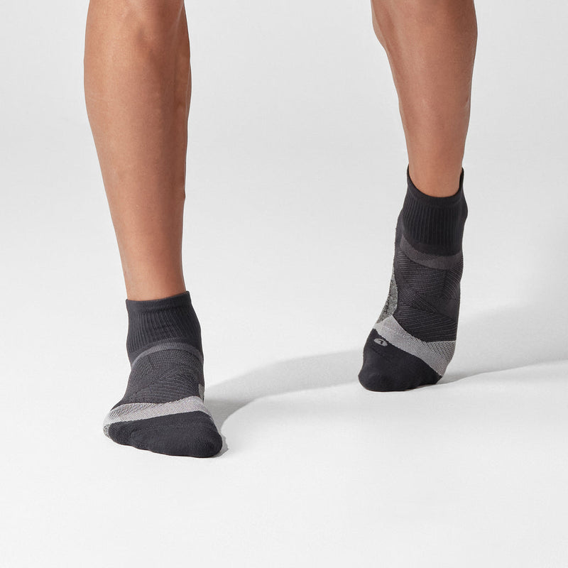 Feetures Elite Light Cushion Quarter socks in dark gray with arch support and moisture-wicking fabric, lifestyle context.