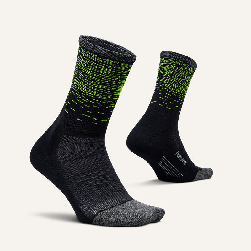 Feetures Elite Light Cushion Reflective Mini Crew socks in black with bright green reflective accents, ergonomic fit, and gray toe detail, angled side view.