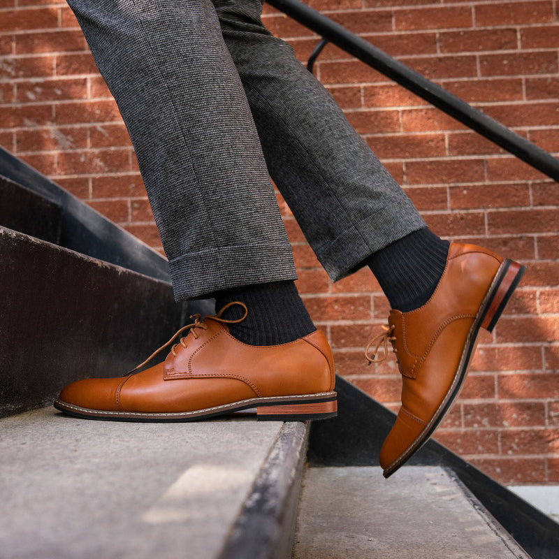 Feetures Everyday Max Cushion Crew socks in black with ribbed texture, worn with dress shoes, lifestyle walking up stairs.