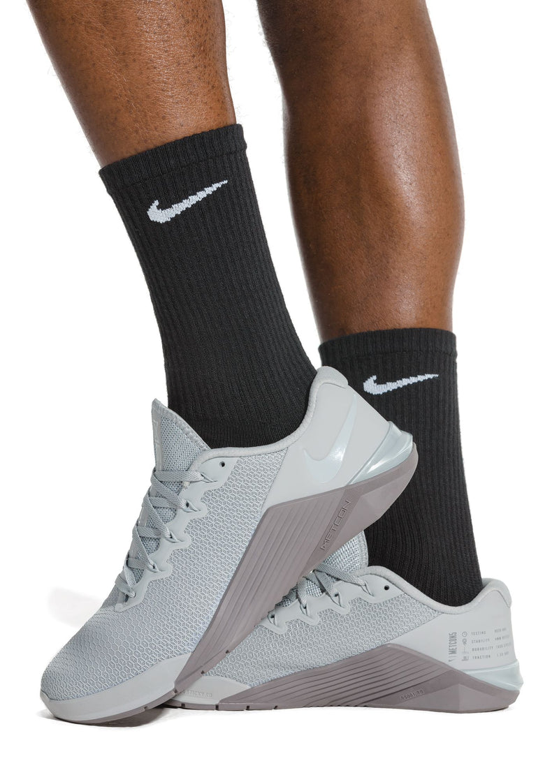 Nike Everyday Plus Cushioned Training Crew Socks in black with ribbed texture and white Nike logo, worn by a person in a training context.