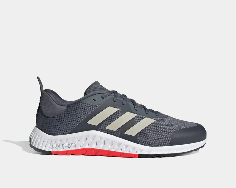 Adidas Everyset Trainer shoes in gray with a breathable mesh upper, light beige three-stripe design, and white sole with red accents, side view.