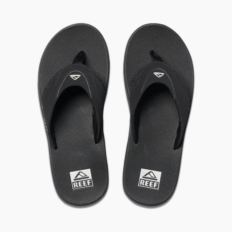 Reef Fanning Flip Flops in black with textured footbed, logo detail on straps, and built-in bottle opener, top view.