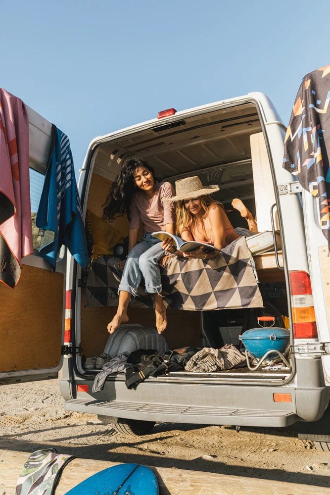 Nomadix Festival Blanket with geometric triangle pattern in beige and black, draped inside an open camper van during outdoor lifestyle.
