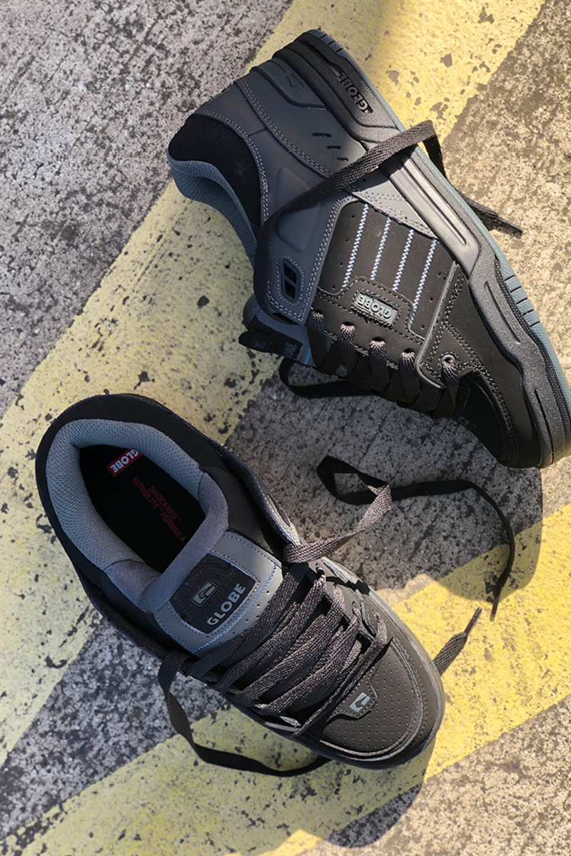 Dark grey Globe Fusion skate shoes with reinforced panels and thick outsole on a textured surface