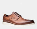 Rockport Garett Wingtip shoes in polished brown leather featuring brogue perforations, white rubber outsole, and lace-up design, side view.