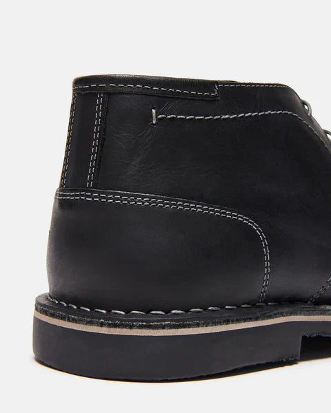 Steve Madden Harken boots in black leather with visible white stitching, back view showing heel and outsole detailing.