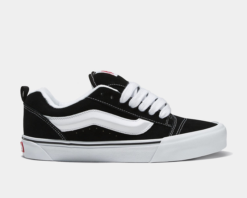 Vans Knu Skool Core sneakers in black suede with white side stripe, thick white laces, and vulcanized outsole, side view.
