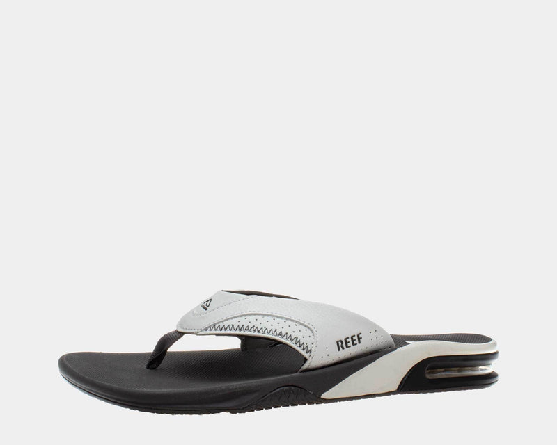 Reef Leather Fanning Flip Flops side view featuring white leather strap, black cushioned footbed, and built-in bottle opener.