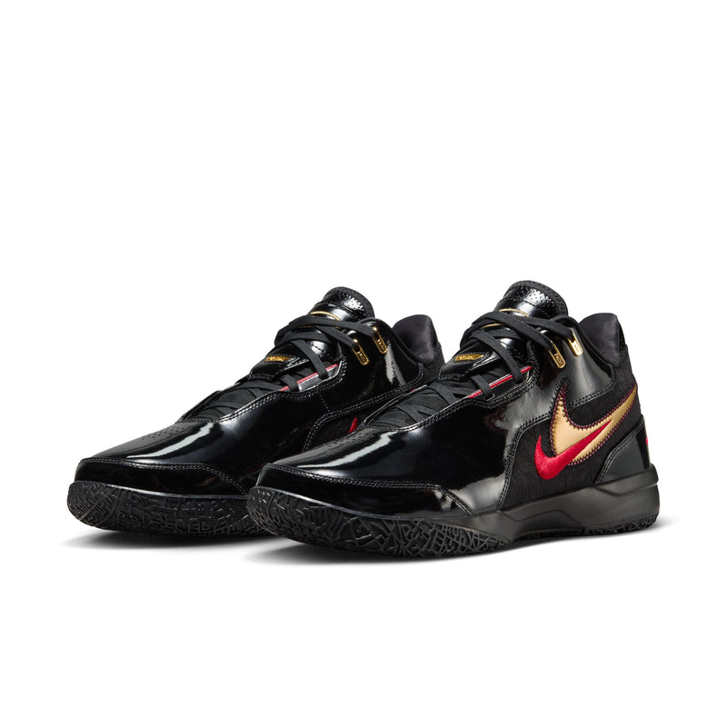 Nike LeBron NXXT Gen AMPD basketball shoes in black with metallic gold accents, red Nike swoosh, and textured rubber outsole, front angle.