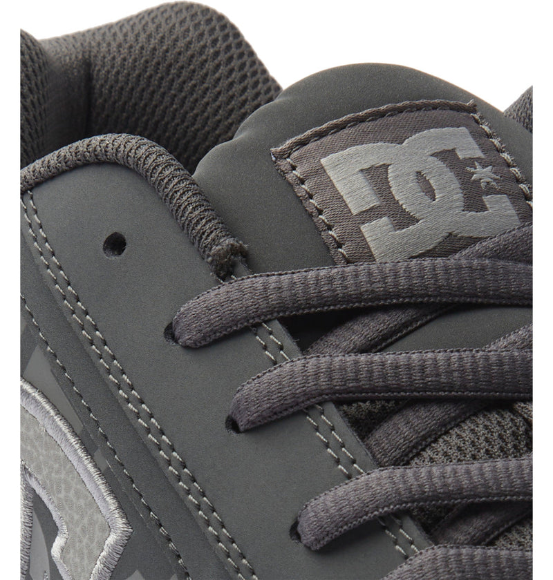Close-up of the Men's Net Shoes by DC Shoes in dark grey, highlighting the DC logo on the tongue, matching grey laces, and a textured upper part—crafted for all-day comfort.