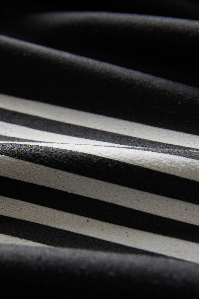Nomadix Mini Towel in black with white stripe design, close-up view showing textured fabric details.
