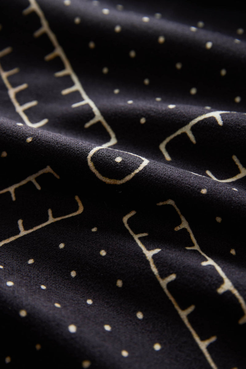 Nomadix Mini Towel in black with beige geometric and dot pattern, close-up view of soft fabric texture.
