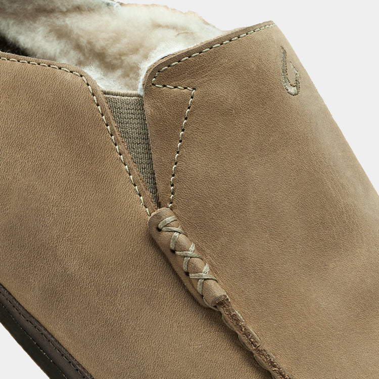 OluKai Moloa Slipper in tan suede with plush shearling lining and hand-sewn moccasin stitching, close-up side view.