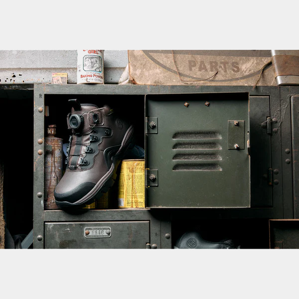 DC WorkCrew Navigator Work Hi Top Comp Toe with Met Guard work boots in black with industrial design and secure lace system, displayed on a workshop shelf.
