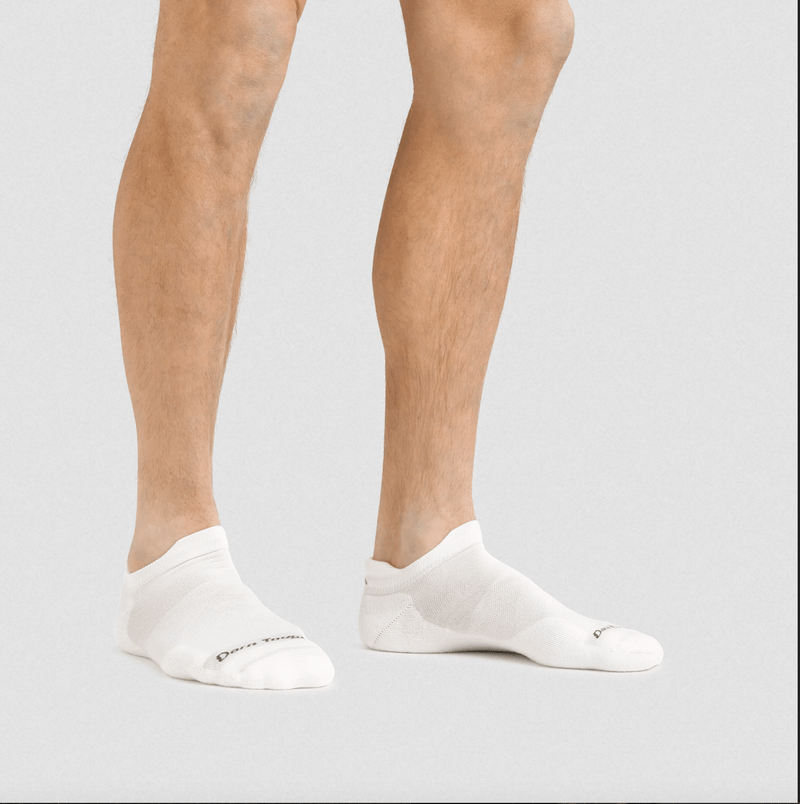 Darn Tough No Show Tab Ultra-Lightweight Running Sock in white with seamless construction, worn by person indoors.