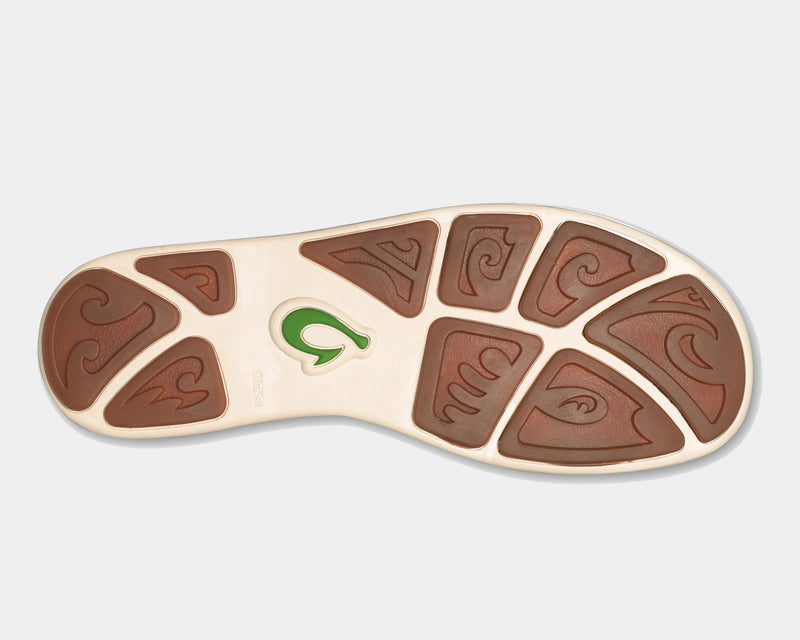 OluKai Nohea Mesh shoes outsole featuring brown rubber pods with wave-inspired patterns and a green logo detail, sole view.