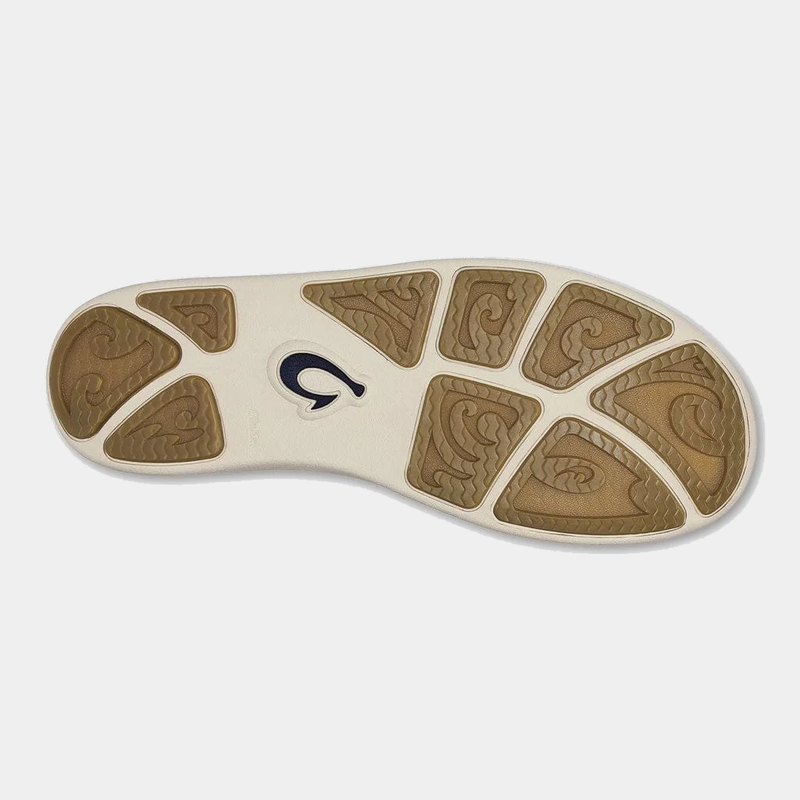 OluKai Nohea Moku shoe sole with textured tan rubber traction pods and wave-like patterns on a white base.