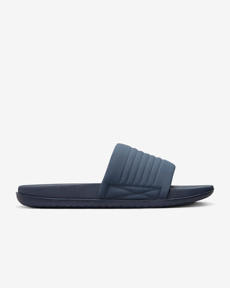 Nike Offcourt Adjustable Slide sandals in navy blue with a padded strap and textured sole, side view.