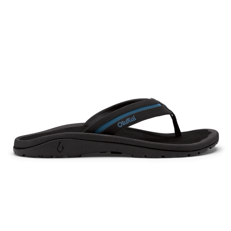 OluKai ʻOhana Pālua sandals in black with blue accents, featuring a comfortable contoured footbed and durable outsole, side view.
