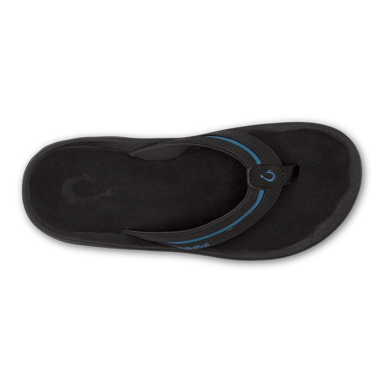 OluKai ʻOhana Pālua sandals in black with blue accents, featuring a contoured footbed and soft strap, top view.