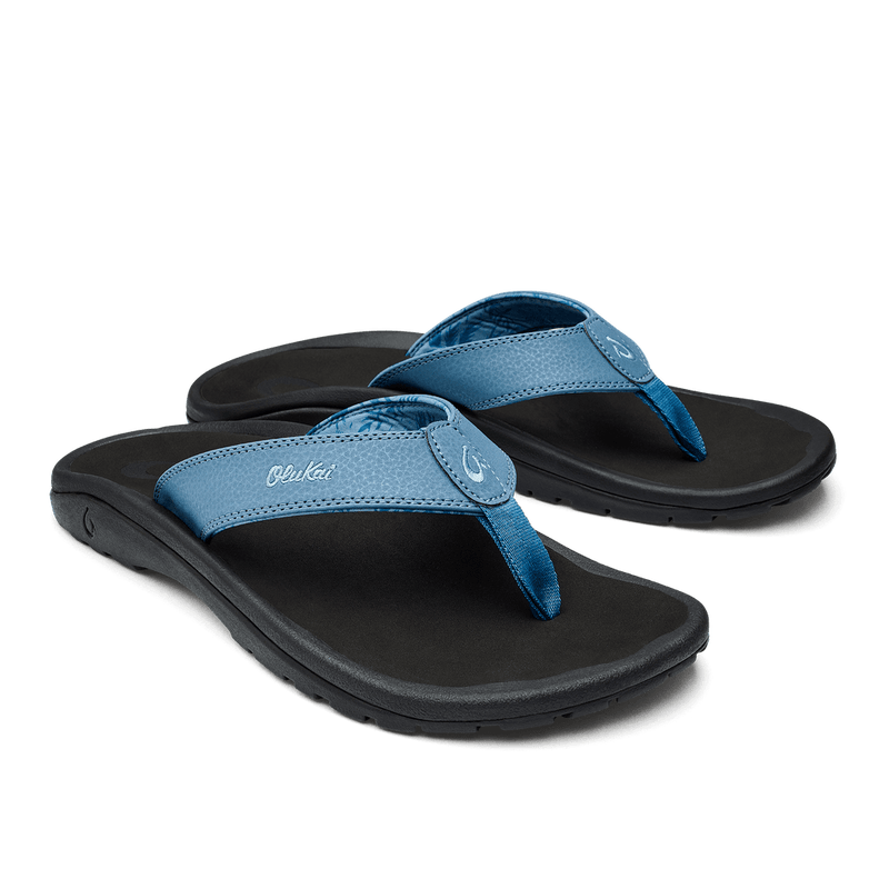 OluKai Ohana sandals in blue with textured straps and black footbed, angled side view showcasing sturdy sole.