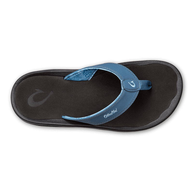 OluKai Ohana sandals with a blue synthetic strap, soft black footbed, and textured outsole, top view.
