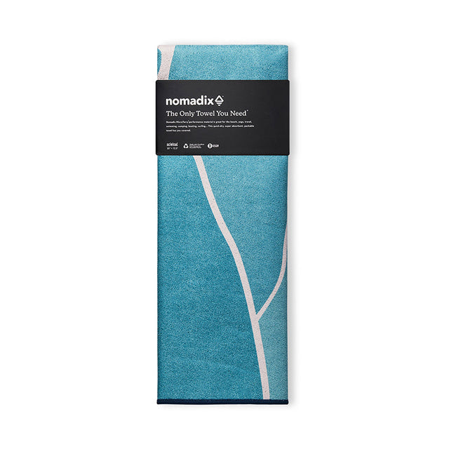 Nomadix Original Towel Big Sur in aqua blue with white abstract design, folded front view showing packaging.