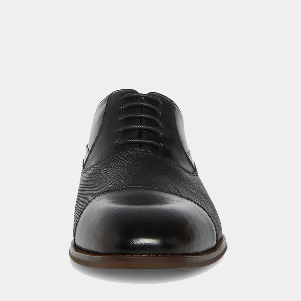 Steve Madden Proctor dress shoes with polished black leather upper and textured detailing, front view showing rounded toe and lace-up closure.