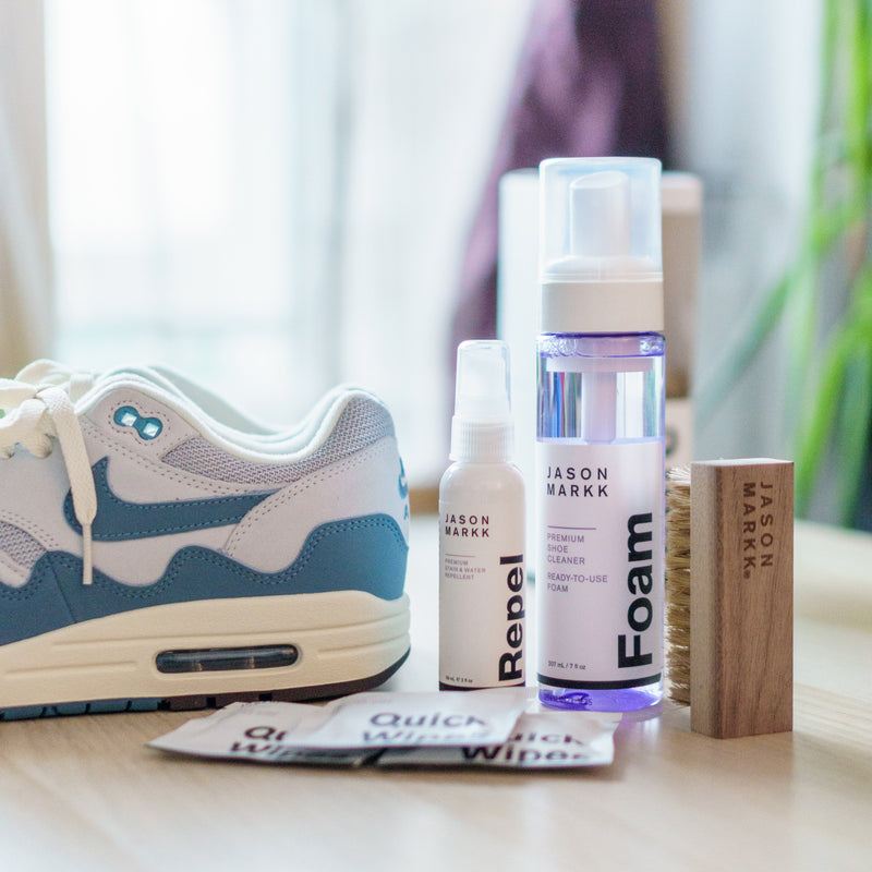 Jason Markk Ready-To-Use Clean Kit for shoes featuring foam cleanser, water repellent spray, wooden brush, and Quick Wipes on a table.