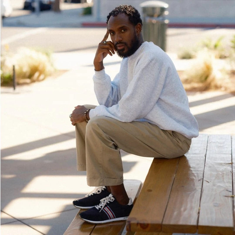 SeaVees Royal Runner sneakers in navy blue with white laces and red stripe accents, worn outdoors on a wooden bench.
