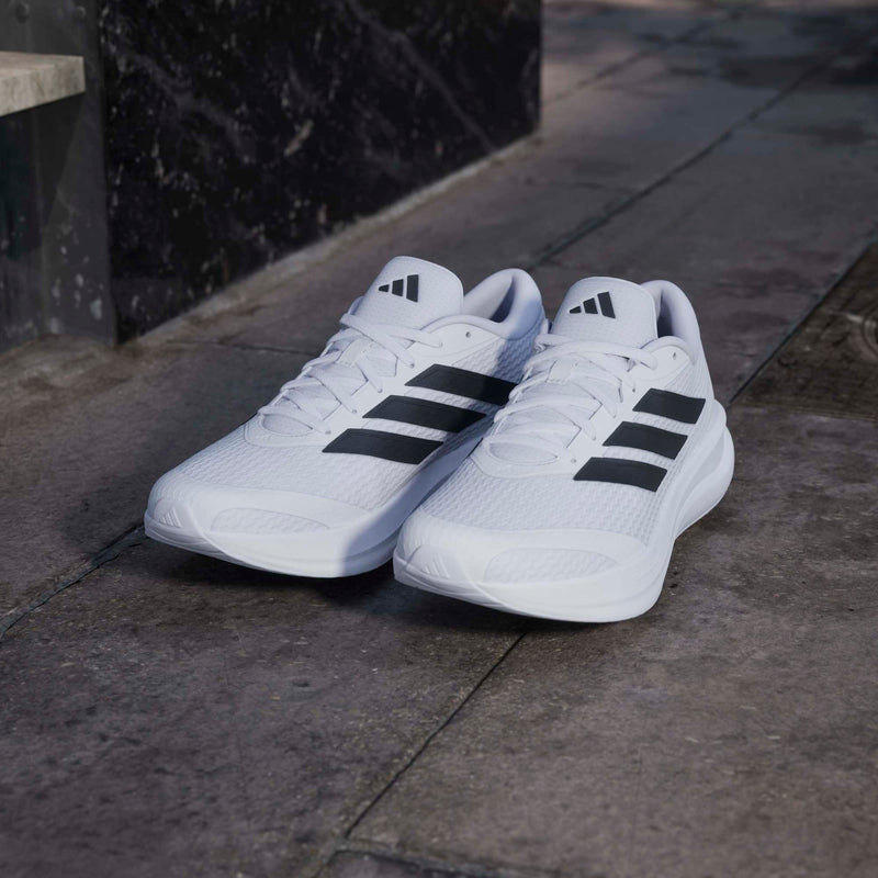 Adidas Runfalcon 6 running shoes in white with black stripes, mesh upper, and lace-up closure, street view.