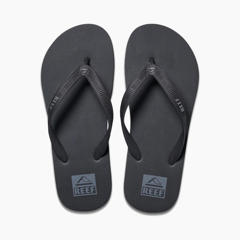 Reef Seaside flip-flops in black with textured footbed and branded straps, top view.