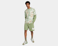 Nike Sportswear Club Shorts in light green with large white Nike logo on left leg, worn by model standing.