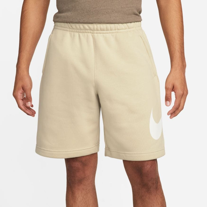 Nike Sportswear Club Shorts in beige with a white Nike Swoosh logo on the left leg, elastic waistband, front view.
