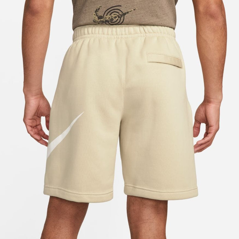 Nike Sportswear Club Shorts in beige with a white Nike swoosh logo, elastic waistband and back pocket, back view.