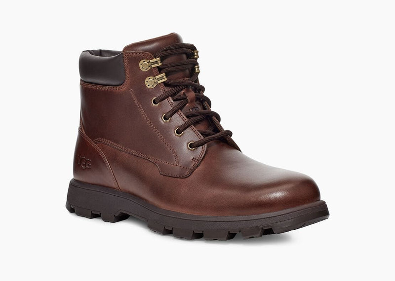 UGG Stenton boots in rich brown leather with padded collar, gold-tone eyelets, and lugged rubber outsole, angled side view.