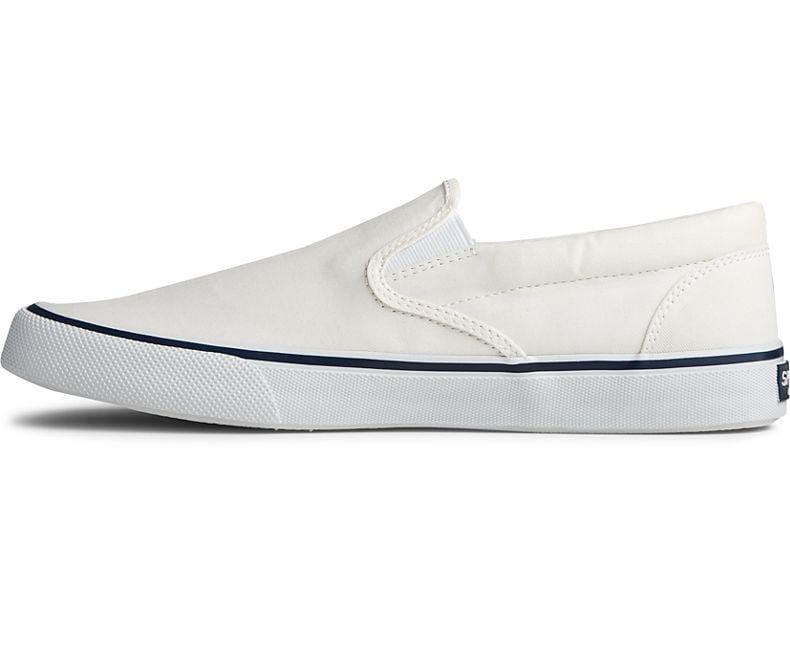 Sperry Striper II Slip On Sneakers in white canvas with elastic side panels and textured white rubber sole, side view.