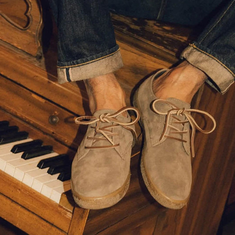 SeaVees Sun-Tans Buck shoes in taupe suede with classic lace-up design and textured tan rubber sole, lifestyle context on piano.