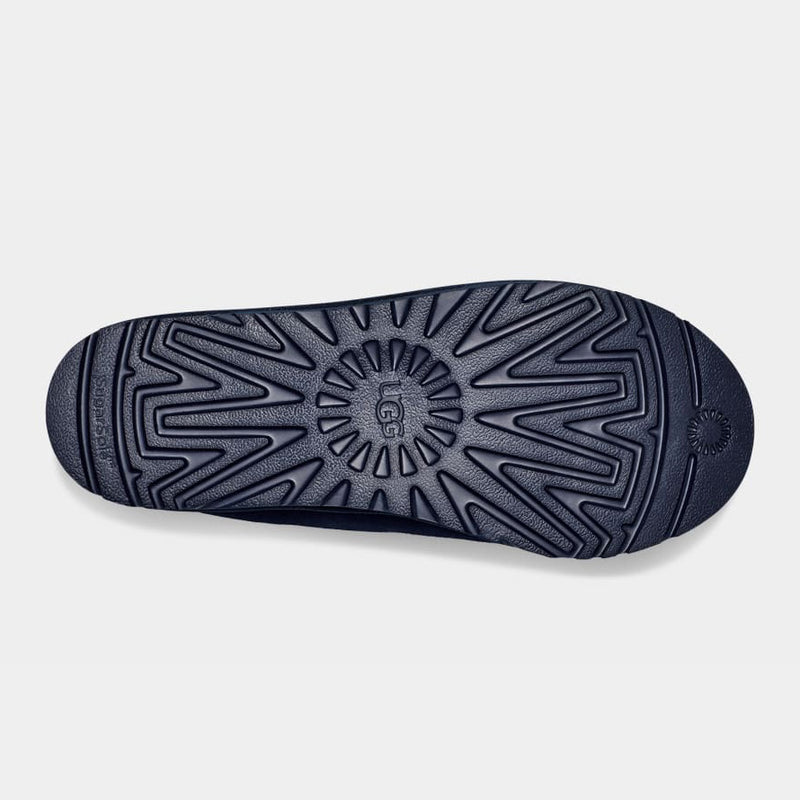 UGG Tasman Slipper outsole in navy blue featuring textured rubber with a radial and zigzag tread pattern, bottom view.