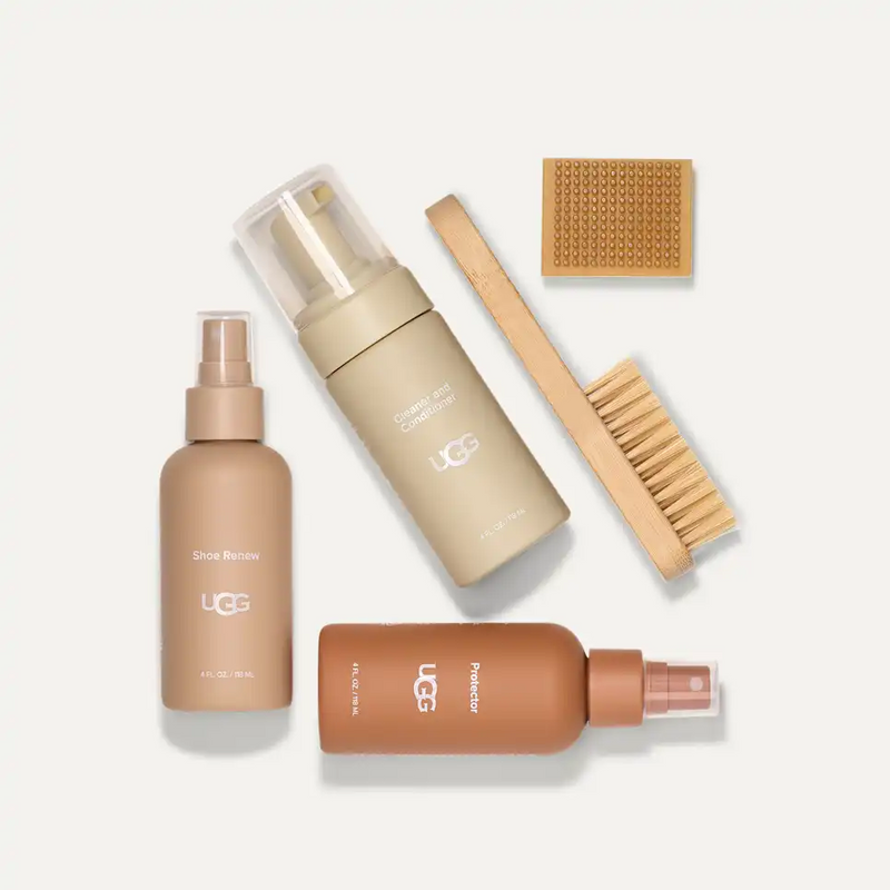 UGG Care Kit with beige cleanser, brown protector, tan shoe renew bottles, wooden brush, and eraser, top view