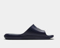 Nike Victori One Shower slide sandals in navy blue, featuring a textured footbed and synthetic strap, side view.