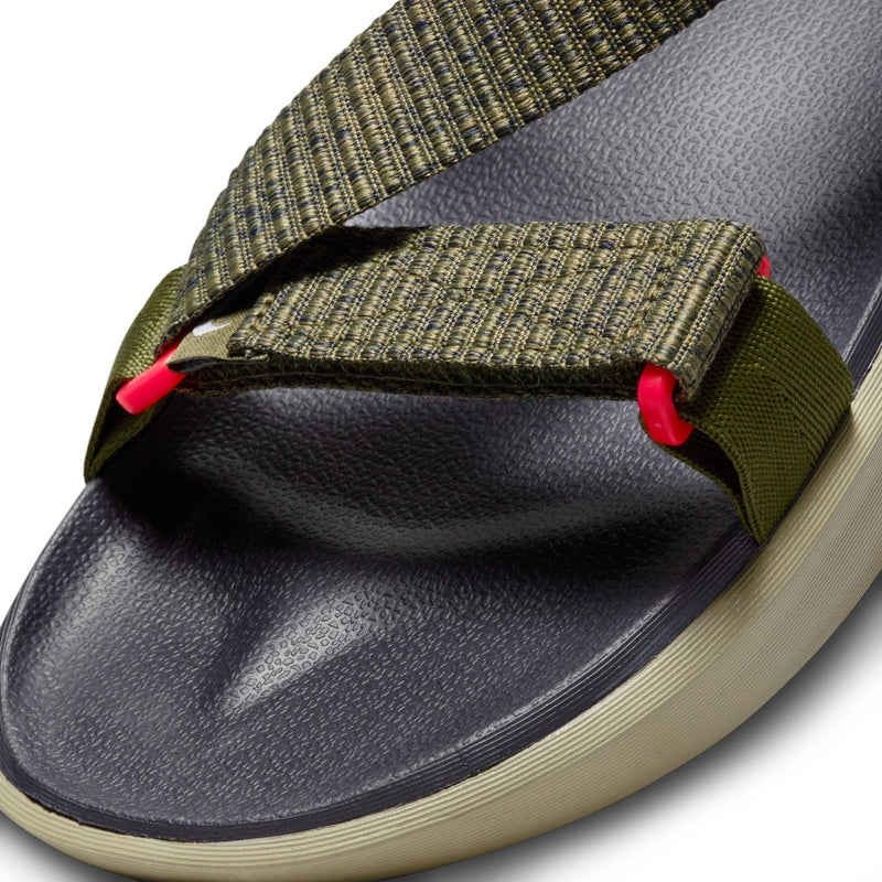 Nike Vista sandals with textured black footbed, olive green woven straps, and vibrant red accents, close-up view of toe area.